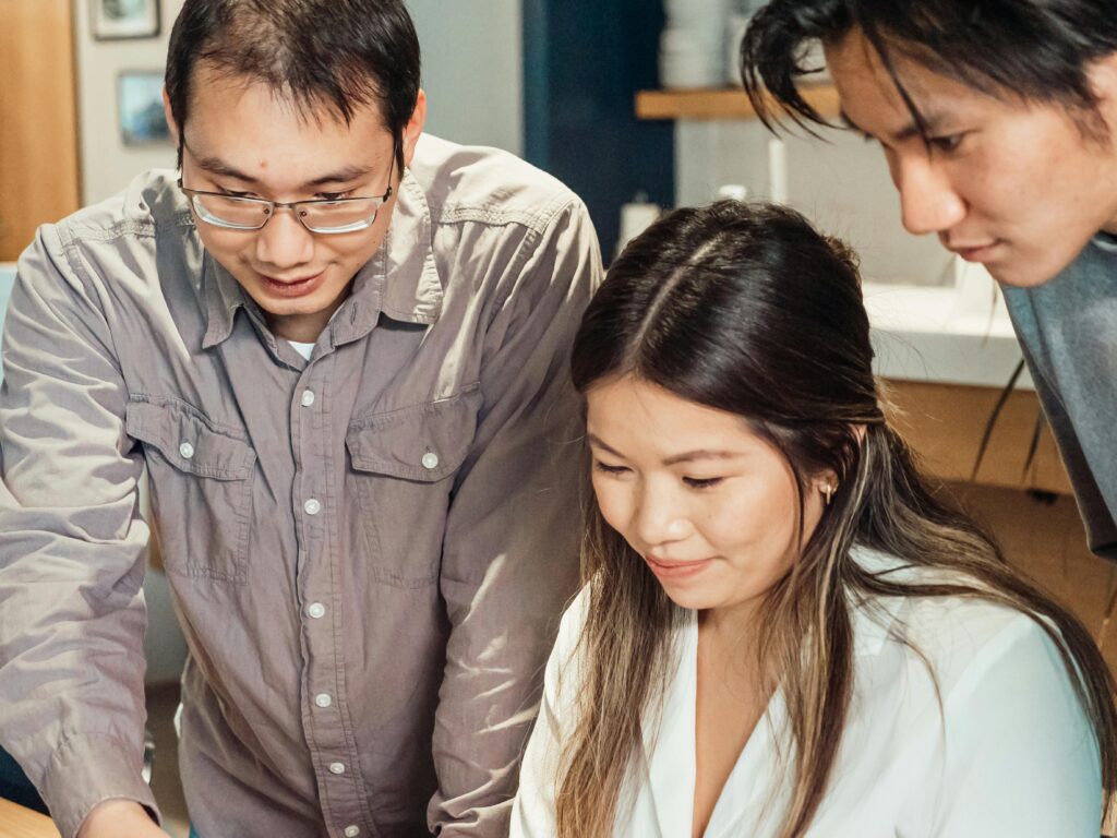 An Asian team collaborating and brainstorming ideas at an office workspace.